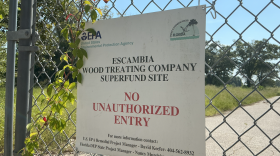 A sign marks the Escambia Wood Treating Company Superfund site, warning against unauthorized entry. The site, which is fenced and closed to the public, is the focus of ongoing environmental cleanup efforts.