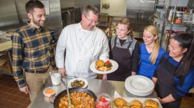 Chef Bob Perry plates up a dish of Ubatuba Paprika Chicken topped with Buttermilk Crème Fresh along with Seared Kale Agrodolce and Cornbread/Rice Cake in the Food Lab, part of the Department of Dietetics and Human Nutrition in the College of Agriculture, Food and Environment at the University of Kentucky. (L to R): Aaron Schwartz, Diatetic Internship Director; Bob Perry, Chef and Food Lab Coordinator; Rachel Thomas, Jordan Brown and Emma Simpson.