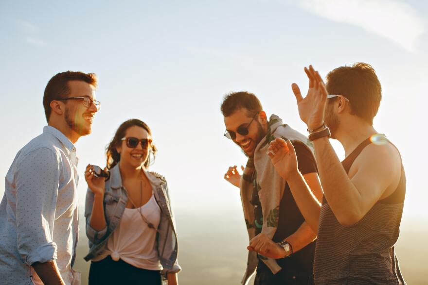 Three men and one woman laughing in the sunset.