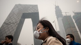 A woman wearing a protective pollution mask walks on a street in Beijing on March 20, 2017. (Nicolas Asfouri/AFP/Getty Images)
