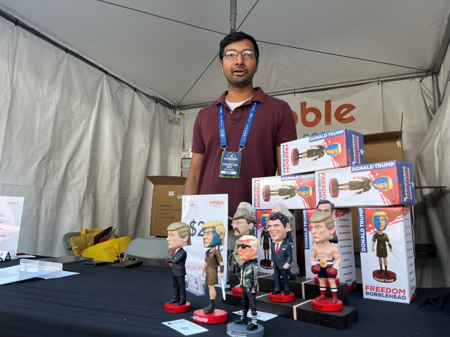 Madan Raj shows off Trump and other political bobbleheads at his RNC vendor tent in Milwaukee. 