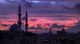 The sky is illuminated red at sunset behind mosque minarets in Rafah in the southern Gaza Strip near the border with Egypt on December 17, 2023 amid continuing battles between Israel and the militant group Hamas. (Photo by SAID KHATIB/AFP via Getty Images)