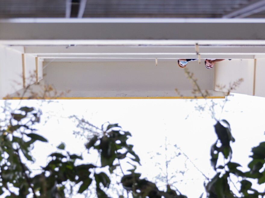 Residents stand on the balcony and people-watch as others play badminton and shuttlecock in the courtyard.