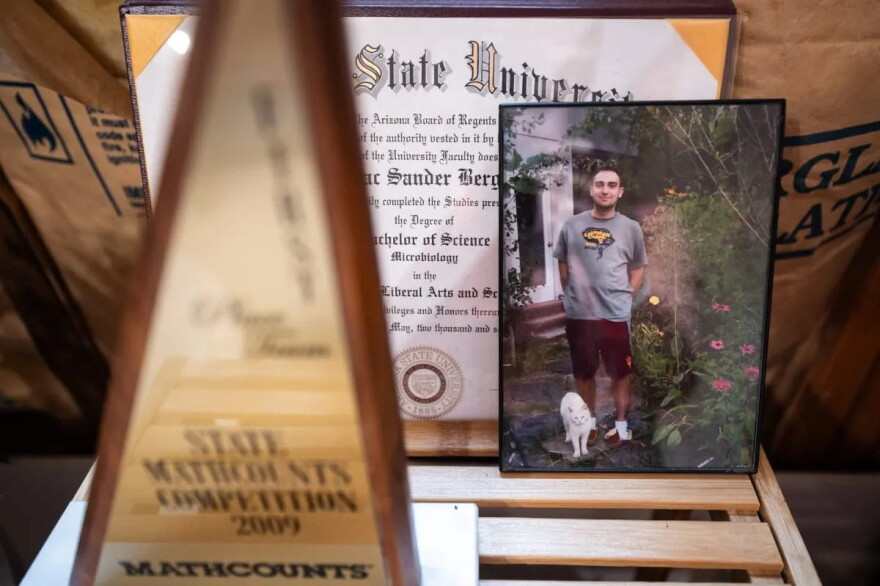 A photo of Isaac Berger with his cat, Frownie, is propped up in his bedroom near his college diploma and a state math competition trophy. A mathematical formula found by police on his computer seemed to calculate how many pills Isaac could take each day without dying.