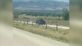 A car driving alongside a road with mountains in the background.