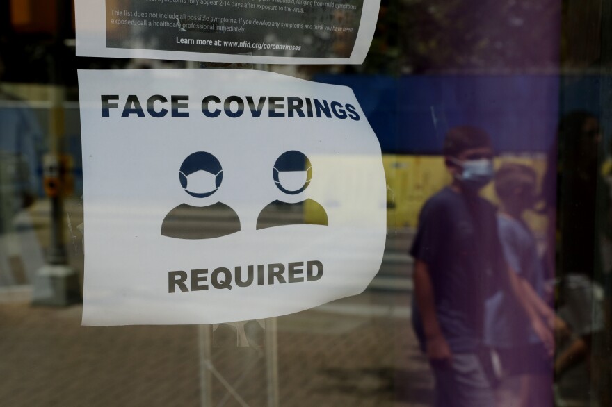 A visitor wearing a masks to protect against the spread of COVID-19 passes a sign requiring masks, Tuesday, July 7, 2020, in San Antonio. 