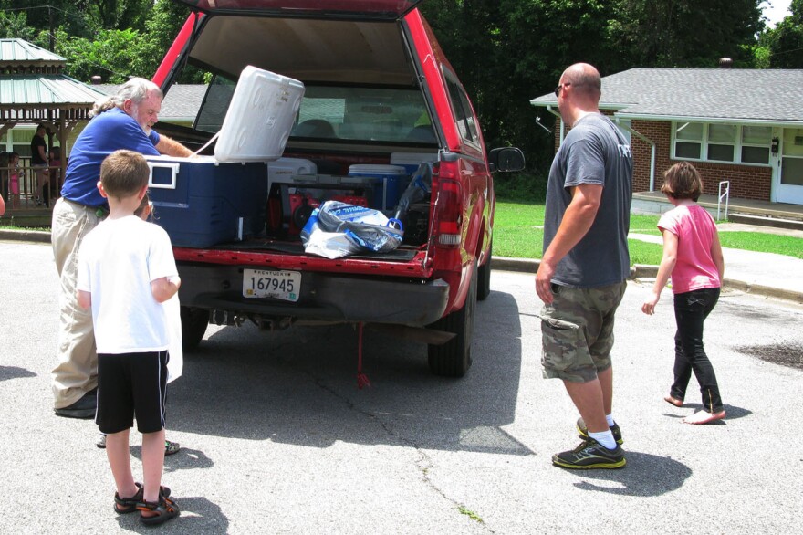 Volunteer Steve Boyd (left) distributes lunches to children from a YMCA truck with the help of YMCA employee Sean Summers (second from right) in Hopkins County, Ky.