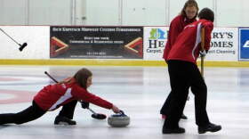 Stephanie Senneker slides the stone at the USA Arena Curling National Championships. Pam Nelson is sweeping in front. Nicole Brinkmann is sweeping in back.