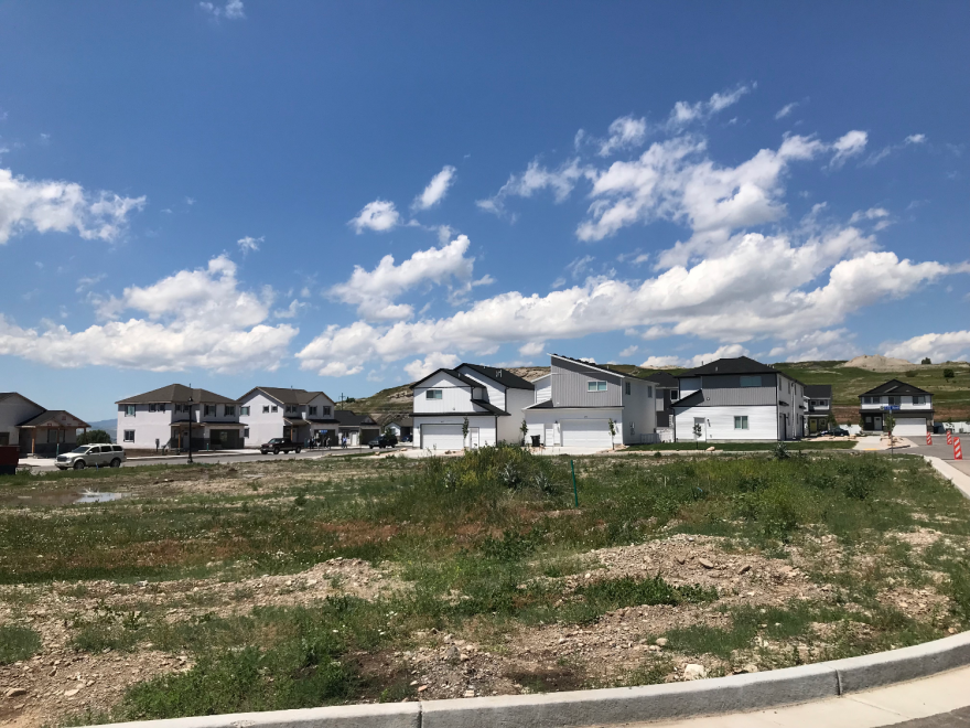 A row of houses leading into a cul-de-sac across a patchy field of grass.