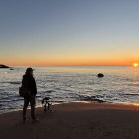 Bugsy Sailor watches the sunrise on October 16, 2025 at Little Presque Isle in Marquette County, Michigan. (credit: Dan Wanschura / Points North)