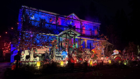 A large house at night is lit up with lights from Halloween decorations.