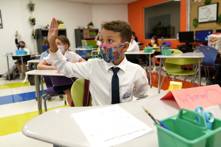 FILE - In this Monday, Aug. 23, 2021, file photo, student Winston Wallace, 9, raises his hand in class at iPrep Academy on the first day of school in Miami.