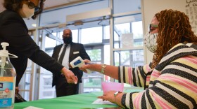 Yvette Richards, director of community connection at St. James United Methodist in Kansas City, checks temperatures before Sunday morning services. The church is hosting vaccination clinics and holding socially-distanced services after shutting down for much of the pandemic.