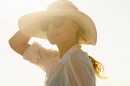 A lady wearing a hat while the sun beams down on her