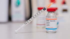 measles mumps and rubella vaccination concept with syringe in vaccine vial and other vials in background
