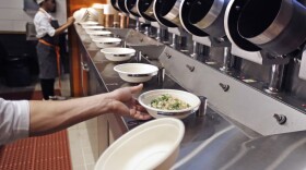 A worker lifts a lunch bowl off the production line at Spyce, a restaurant which uses a robotic cooking process, in Boston, Thursday, May 3, 2018. Robots can't yet bake a souffle or fold a burrito, but the new restaurant in Boston is employing what it calls a "never-before-seen robotic kitchen" to cook up ingredients and spout them into a bowl. (Charles Krupa/AP)