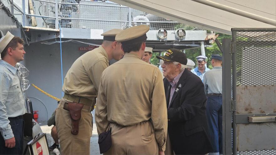 World War II veteran Army SSgt. John Long, in blue jacket, talks with WWII reenactors Daniel Morgan, left in brown, and Lukas Smith at Buffalo and Erie County Naval and Military Park.