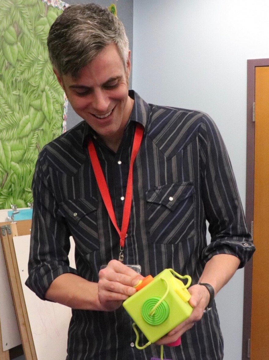 Cameron Burris, a librarian in youth services, demonstrates one of the sensory toys, OombeeCube, involving engagement with shapes and colors. (Christine Guerrero/WUFT News)