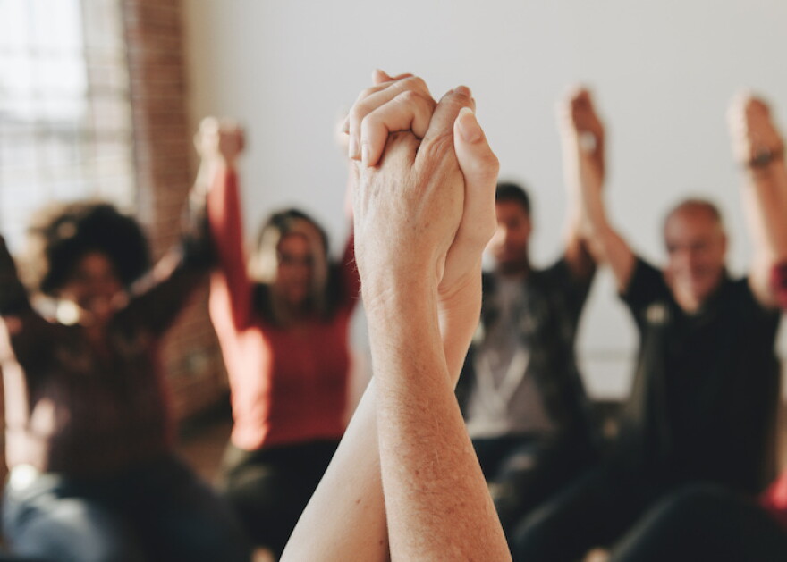 Group of diverse people holding hands up in the air