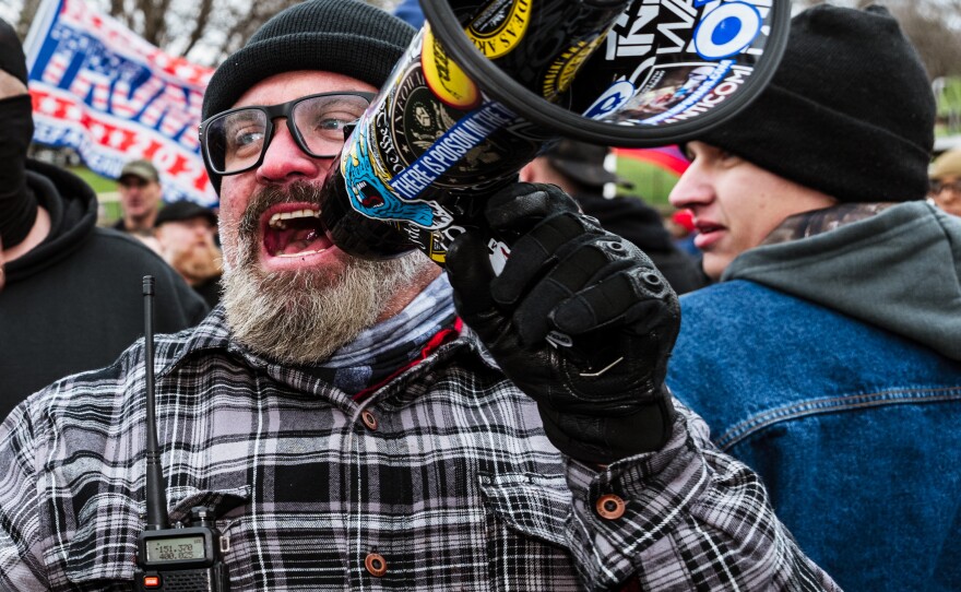 Joe Biggs, a member of the Proud Boys, speaks into a megaphone in front of the U.S. Capitol on Jan. 6. Biggs, charged in the Capitol riot, assisted in the group's growth and also has a history of violent rhetoric.