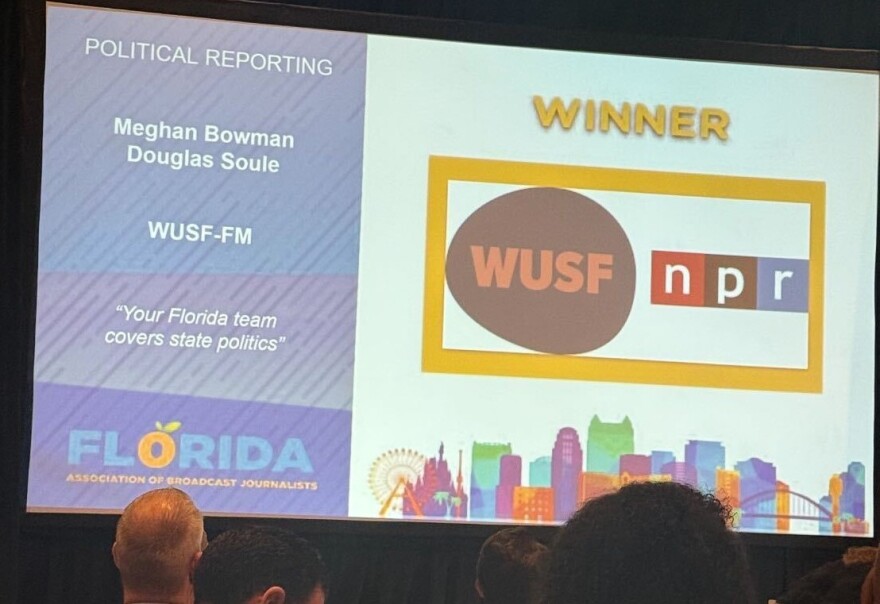 A large screen projects WUSF's logo with the text winner for political reporting Meghan Bowman and Douglas Soule WUSF-FM "Your Florida team covers state politics" 