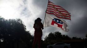 Republican supporter Dolly Schultz holds flags outside of a polling place at SSGT Willie de Leon Civic Center at the start of voting in Uvalde, Texas, on November 8, 2022. (Photo by Mark Felix / AFP) (Photo by MARK FELIX/AFP via Getty Images)