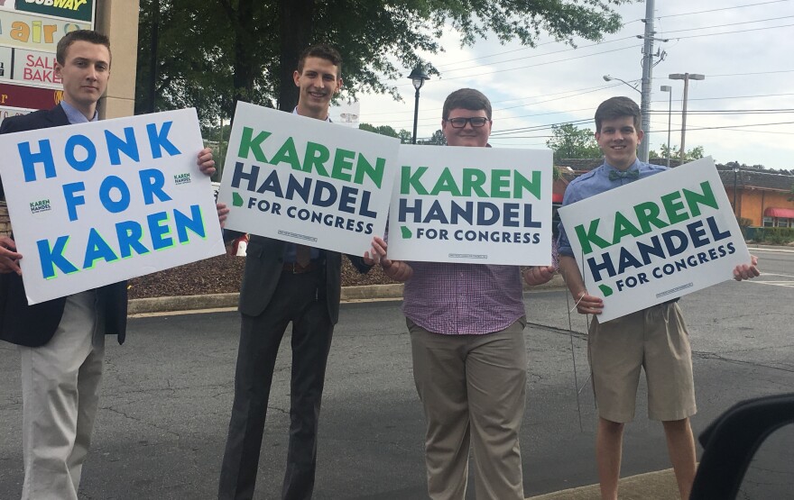 Supporters for Republican Karen Handel wave signs along a highway in Sandy Springs, Ga.