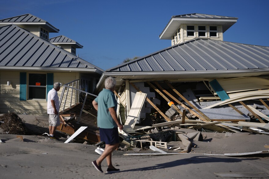 Property owners who preferred not to be named assess damage to their home and business, which bears orange notices calling for demolition, after the passage of Hurricane Milton, on Manasota Key in Englewood, Fla., Sunday, Oct. 13, 2024.