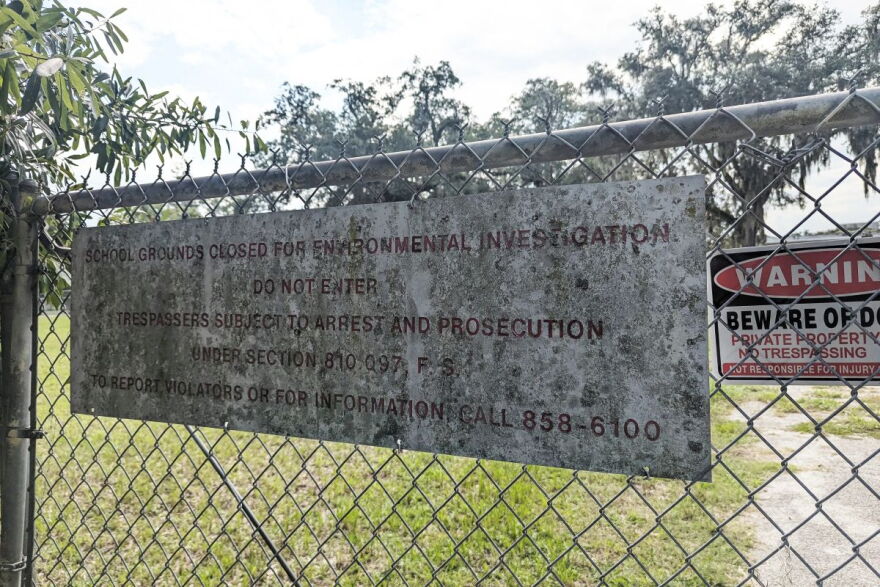 A sign on the fence in front of school closed for environmental contamination 