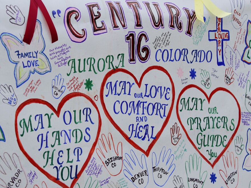A banner with messages has been put up outside the theaters in Aurora, Colo., where 12 died and 58 were wounded early Friday.