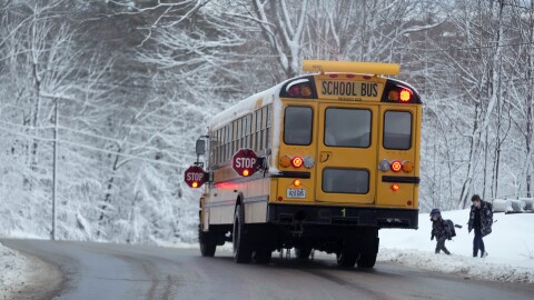 Children are picked up by their school bus following a day off due to a winter storm, Wednesday, March 15, 2023, in Poland, Maine. The storm dumped heavy, wet snow on parts of the Northeast, causing tens of thousands of power outages.