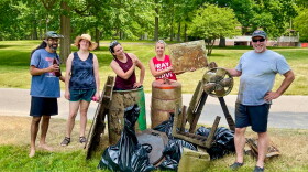 A group of people is posing with trash and debris they pulled from a river in Lansing.