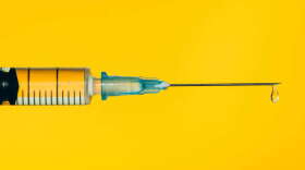 Closeup contemporary disposable syringe with drop of fluid medication on needle placed against vivid yellow background. Vaccination is the most anticipated procedure of the year. Research of coronavirus disease protection concept. Covid-19 vaccine studies.