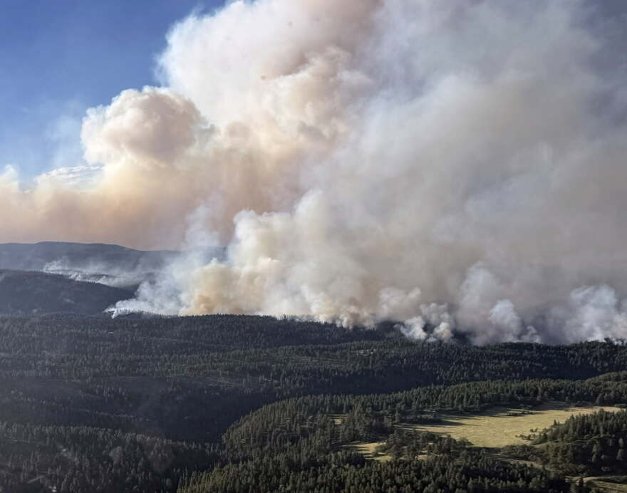 Smoke rising from a wooded foothills area.