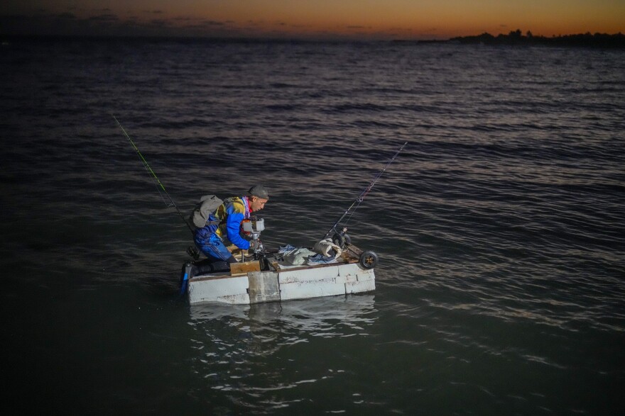 A man on a makeshift "corcho" or  raft prepares to fish at dawn
