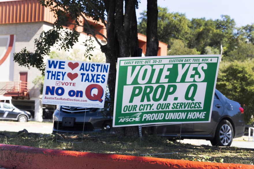 Two voting signs one reading No on Prop Q the other Vote Yes on Prop Q are shown on a curb. 