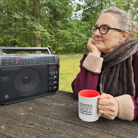 Christy L'Esperance holds an IPR mug and listens to an FM radio