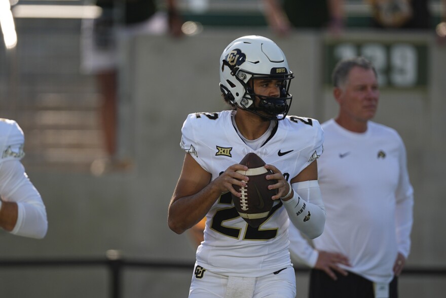 Colorado quarterback Dominiq Ponder, in a white jersey and helmet, holds a football