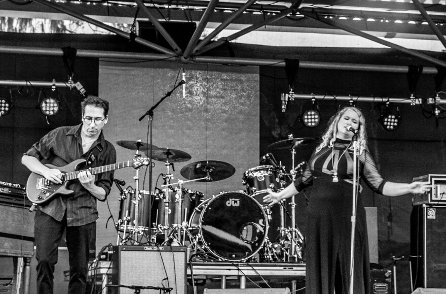 A black and white photo of two musicians on stage, one singing and one playing guitar.