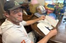 Man sits at table with pile of mail.