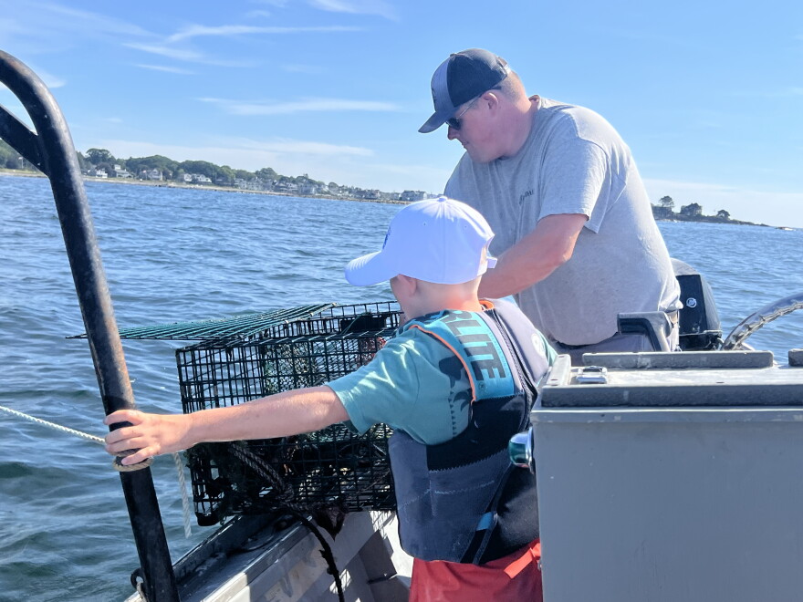 Chris Weltch and his son Calvin, reel in a lobster trap off the coast of Kennebunk, ME.