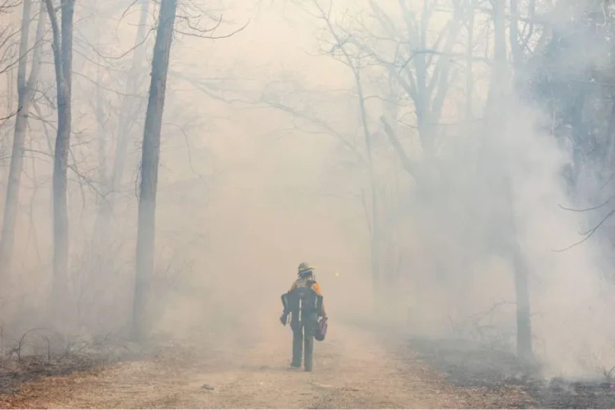 Fire fellow Piper Morris walks through a thick cloud of smoke as she and other members of The Nature Conservancy begin a burn unit March 25, 2026, at Giant City Lodge in Makanda, Illinois.