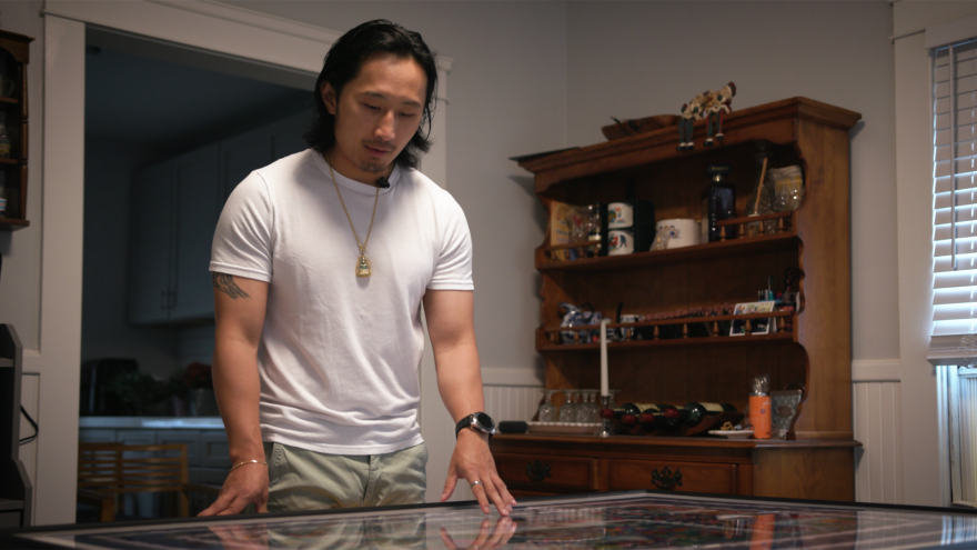 Johnny Kue examines a Hmong tapestry displaying the journey from Laos, to Thailand, to the United States.