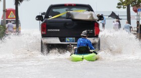 A truck pulls a man on a kayak on a low-lying road after flooding in the aftermath of Hurricane Ian, in Key West, Fla., Wednesday afternoon, Sept. 28, 2022.