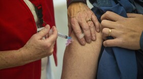 A first responder from Needham Fire Department receives the Moderna COVID-19 vaccine at Rosemary Recreational Center in Needham. (Jesse Costa/WBUR)