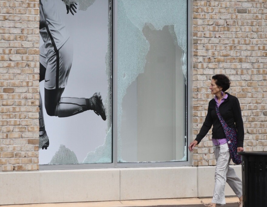 Kansas City resident Rebecca Smith walks past a smashed display window in a parking garage along Wyandotte Street at the Country Club Plaza.