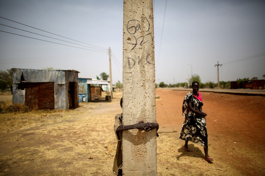 The town of Bentiu, in South Sudan, has been nearly abandoned. On the main road, a boy hides behind a telephone pole.