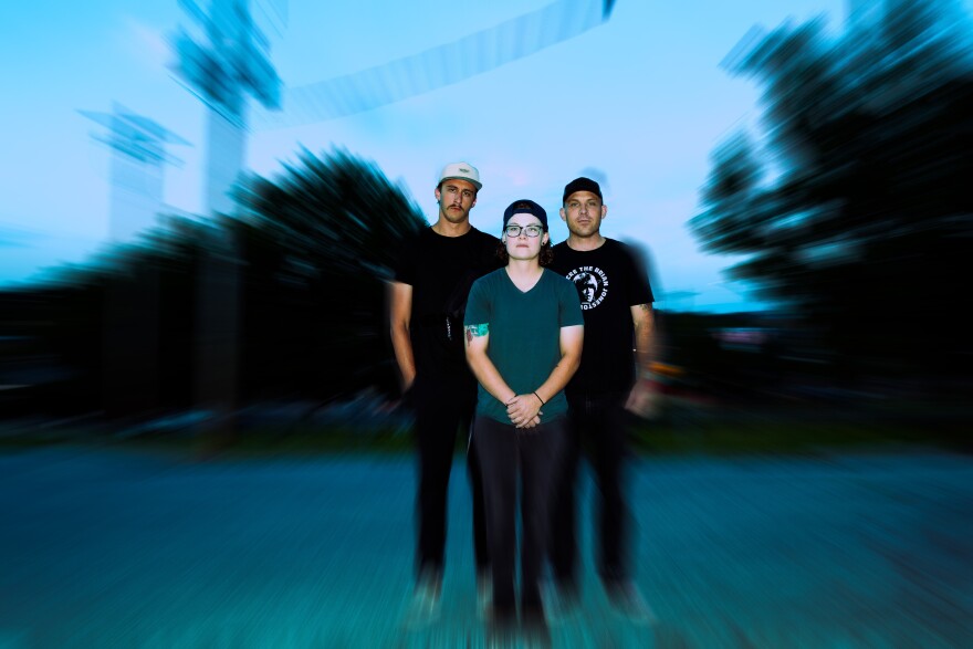 Three people stand outside with a blank expression with a blurring effect around them.