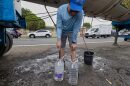 A man fills water jugs from a tanker truck amid drought-driven water rationing, in the Cupey sector of San Juan, Puerto Rico, Wednesday, Aug. 5, 2026.