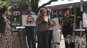 Rep. Natasha Hill (D-Spokane) speaks to gatherers after the guilty verdict handed to the "Spokane 3." She is flanked by illustrations of defendant Bajun Mavalwalla II, whose father is behind her, second from right.